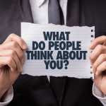 Close-up van man in pak die bord vasthoudt met de tekst 'What do people think about you?'