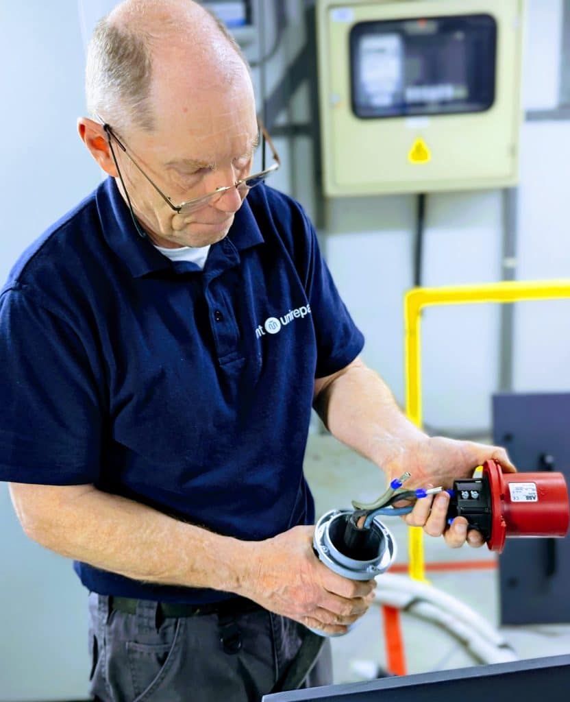 Technicus in blauwe polo voert technische inspectie uit op rode connector