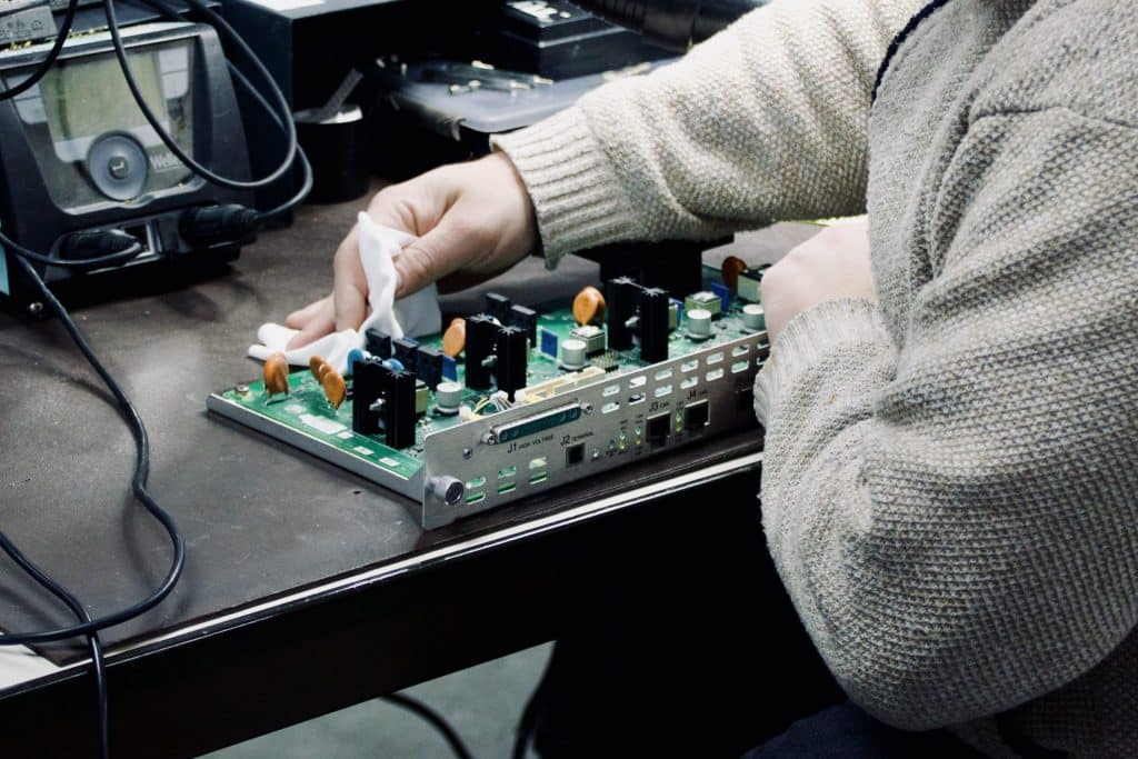 Technicus inspecteert printplaat op werkbank